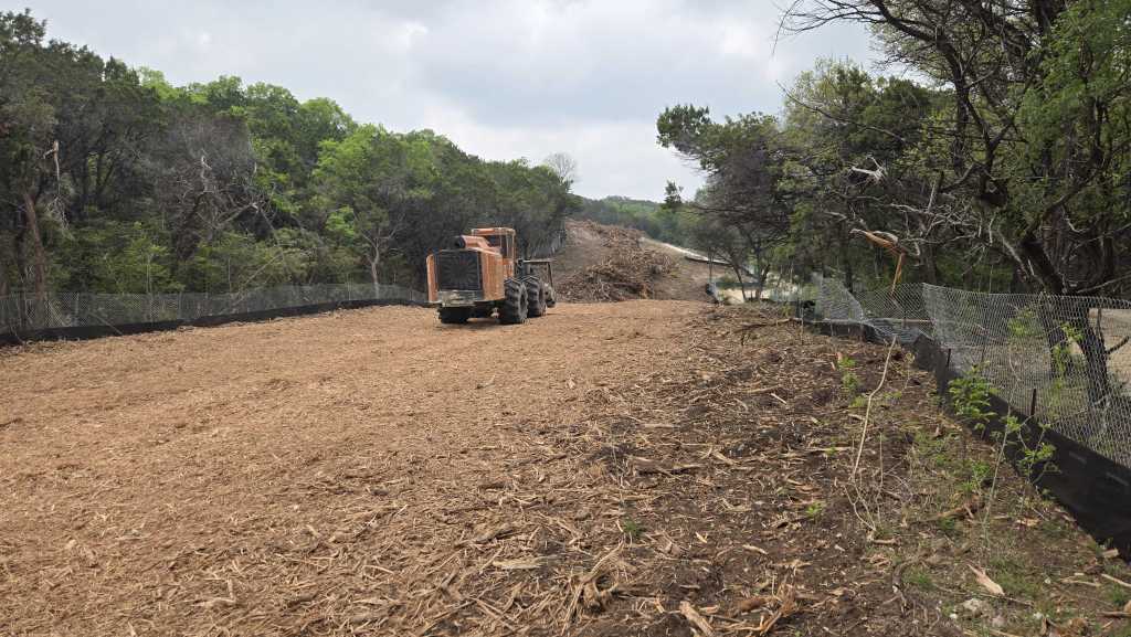Brush piles stacked before mulching on an Austin TX property