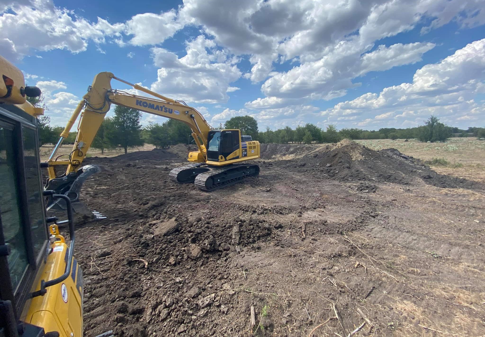 View from the excavator cab over freshly graded ground on a Central Texas job