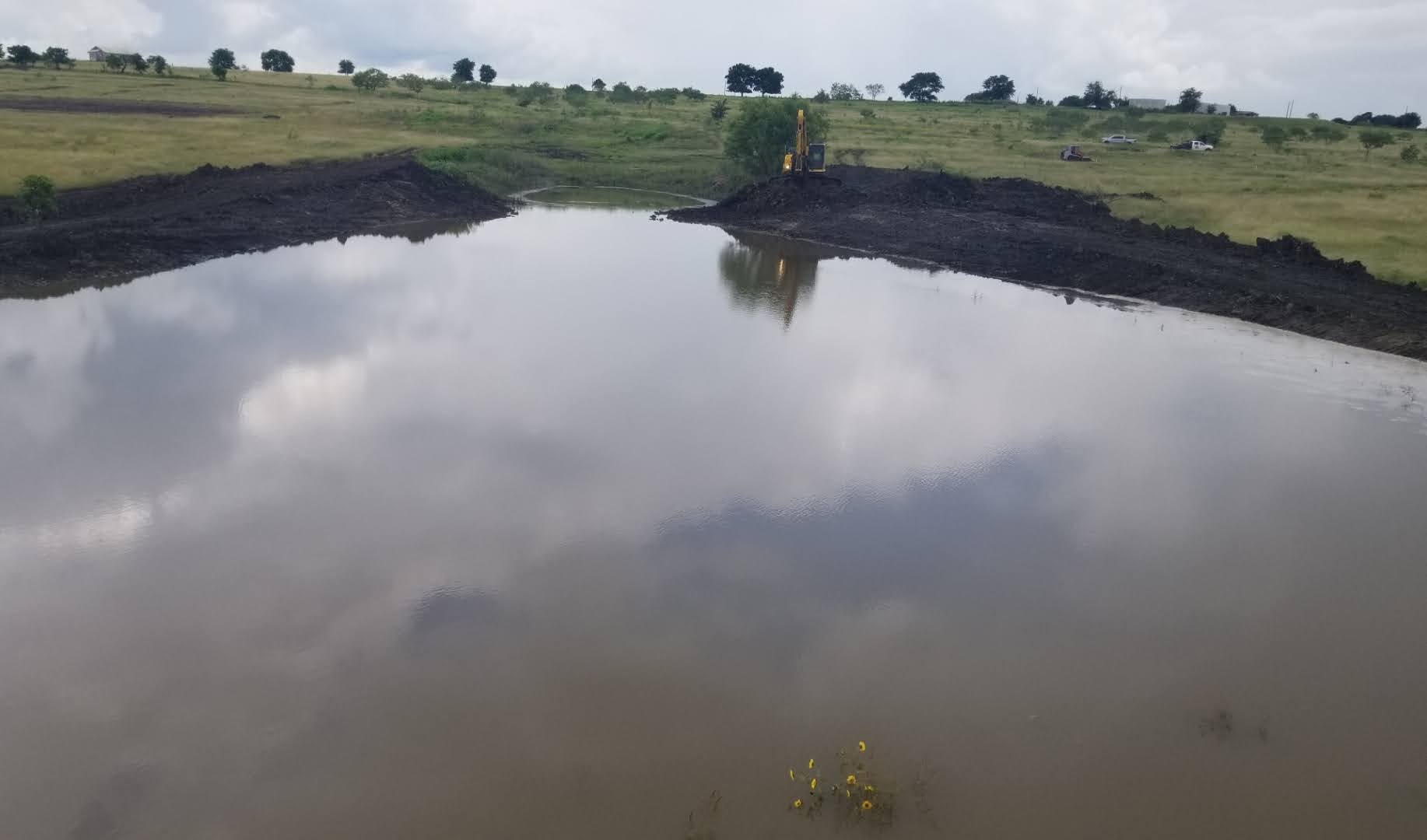 Finished quarter acre pond holding water in Bastrop Texas