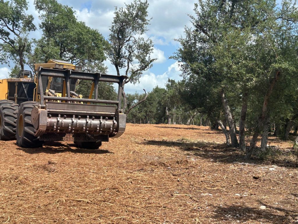 Mulcher grinding brush piles in the river country near Luling TX